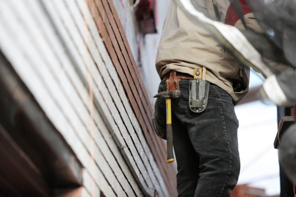 Free Close-up of a construction worker with hammer and tools, focused on the job. Stock Photo