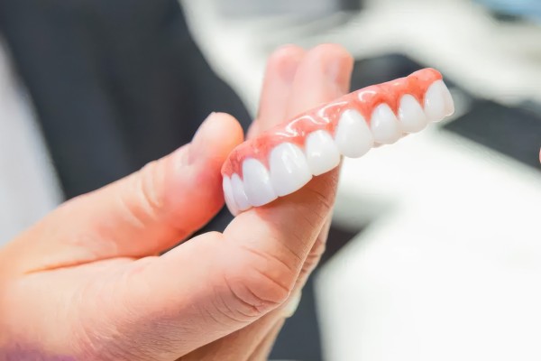 A hand holding a set of full mouth dental implants