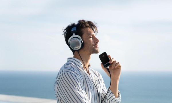 A person wearing headphones and holding a phone

Description automatically generated