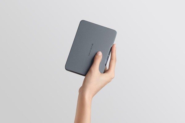 A hand holding a grey rectangular object

Description automatically generated