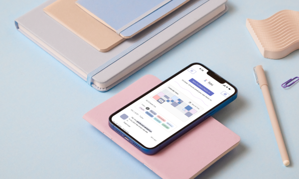 A phone that has the Habit Guided Journaling app open on a flatlay view of a cute desk with soft pastel notebooks, pencils and other stationary.