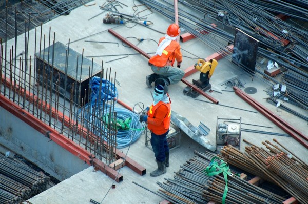 Large modern steel building under construction with exposed structural steel framing against a clear blue sky